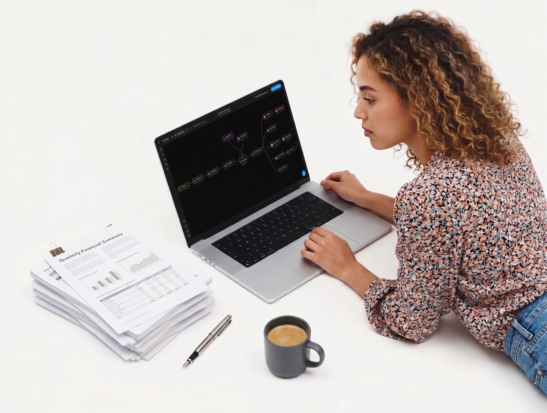 An operator reviewing a Flero workflow on her laptop, beside a stack of printed reports and a coffee